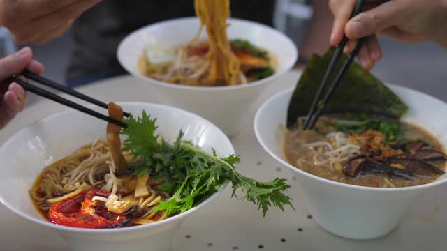 素食的亚洲美食。三个人用筷子在拉面汤中搅拌配料的侧面图视频素材