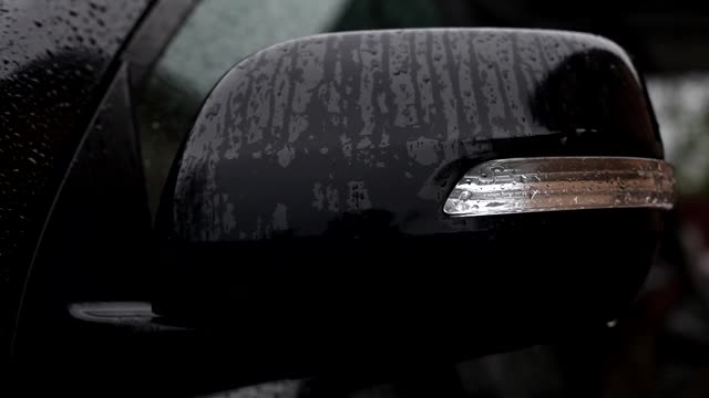 一位妇女在擦拭汽车后视镜上的雨滴。视频素材