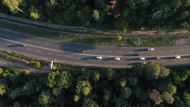 日落时分，汽车在森林中平稳的转弯道路上行驶。从空中看。鸟瞰图。视频素材