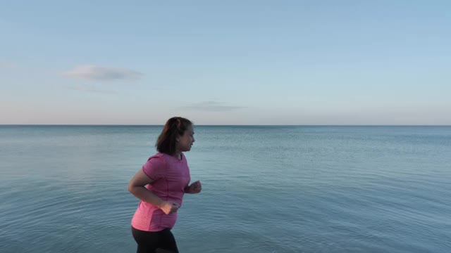 亚洲女人早上在海滩上跑步视频素材