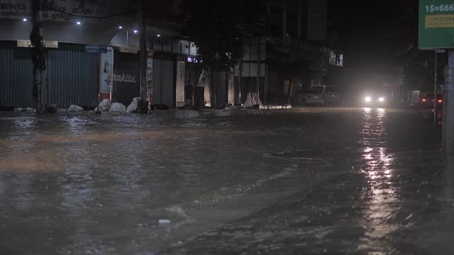 一辆旅游巴士在晚上季风降雨后穿过被水浸透的街道视频素材