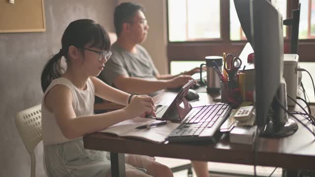 亚裔中国女孩在家学习在她父亲的家庭办公室参加在线课程视频素材