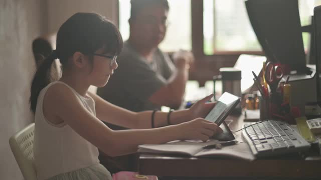 亚裔中国女孩在家学习在她父亲的家庭办公室参加在线课程视频素材