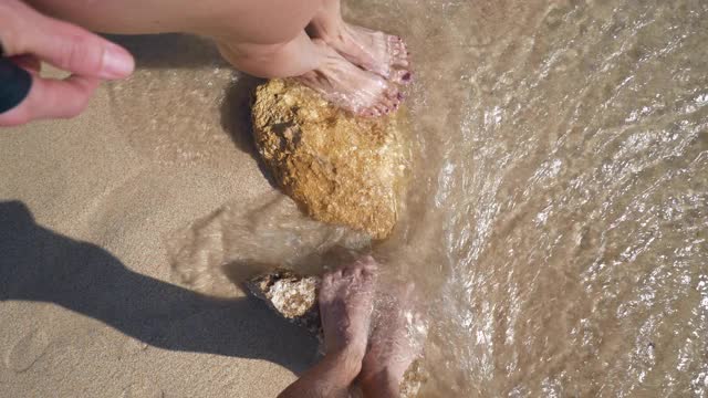 阳光明媚的一天巴厘岛海洋干净的水海浪夫妇脚在沙子慢镜头全景4k印尼视频素材