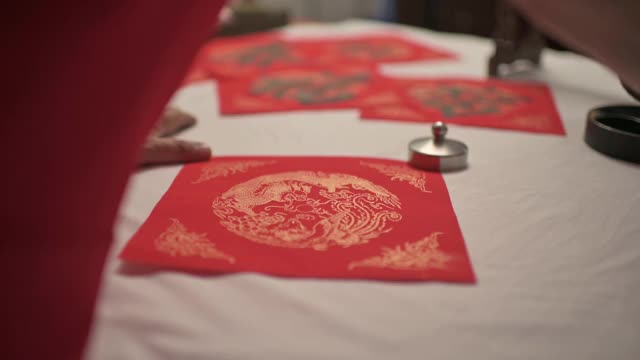 亚洲华人男性练习书法的手，为即将到来的中国新年庆祝家庭装饰目的繁荣和良好的措词写在一张红色的纸上视频素材