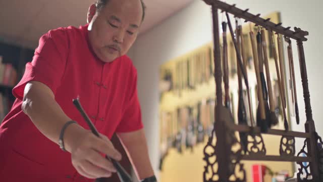 亚洲华人男性练习书法，为即将到来的中国新年庆祝家庭装饰目的与繁荣和良好的措辞写在一张红色的纸上视频素材