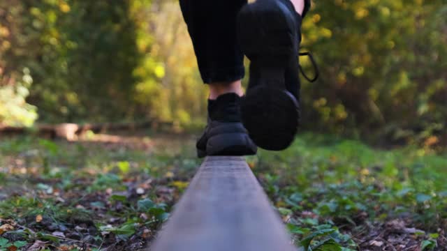 年轻女性在铁轨上的铁轨上行走。腿的后视图。慢动作视频素材