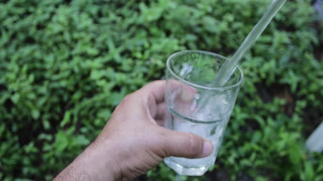 在花园里把水倒进玻璃杯里视频素材