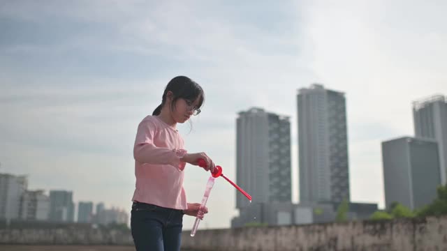 亚洲华人的兄弟姐妹年轻的女孩妹妹玩泡泡在晚上日落户外视频素材