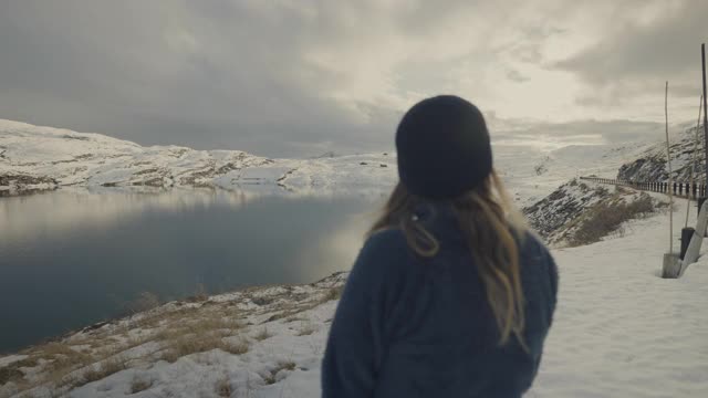 在挪威的湖边徒步旅行的女人:冬天的颜色和心情视频素材