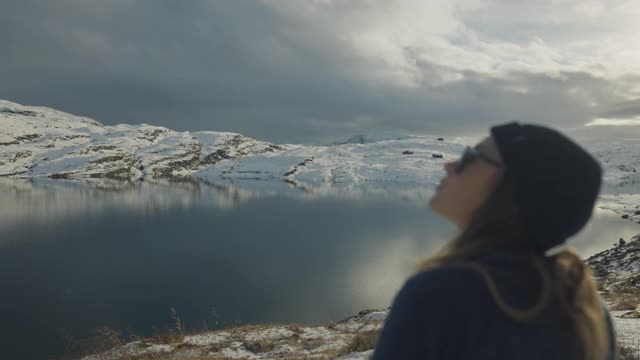 在挪威的湖边徒步旅行的女人:冬天的颜色和心情视频素材