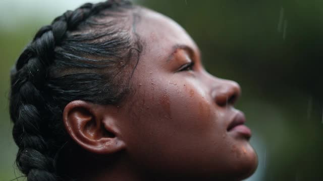 黑女孩在雨中淋浴。特写非洲年轻女子仰望天空与希望，同时下雨视频素材