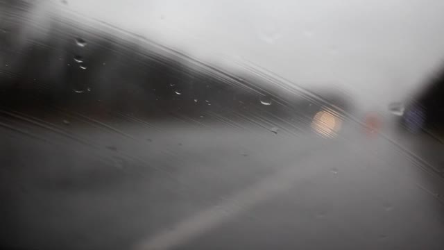 秋雨打在挡风玻璃上，以道路为背景视频下载