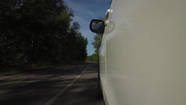 驾驶汽车，POV，特写车轮旋转在乡村道路与树木和蓝天视频素材