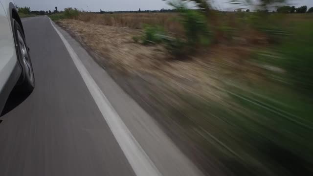 驾驶着汽车，POV，特写车轮在田野和蓝天的乡村道路上旋转视频素材