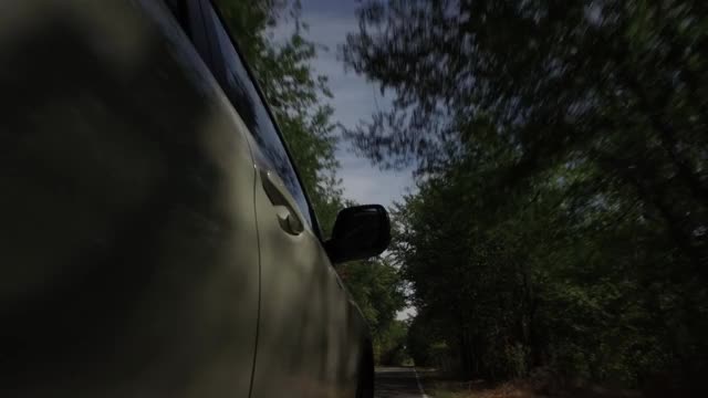 驾驶汽车，POV，特写车轮旋转在乡村道路与树木和蓝天视频素材