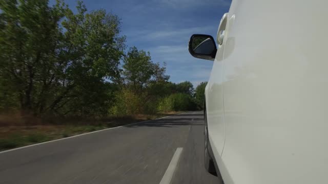 驾驶汽车，POV，特写车轮旋转在乡村道路与树木和蓝天视频素材