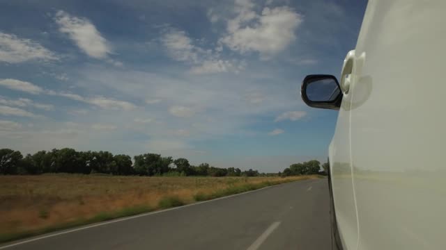 驾驶着汽车，POV，特写车轮在田野和蓝天的乡村道路上旋转视频素材