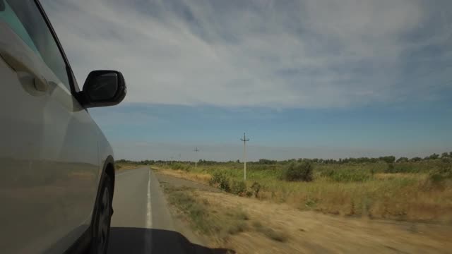 驾驶着汽车，POV，特写车轮在田野和蓝天的乡村道路上旋转视频素材