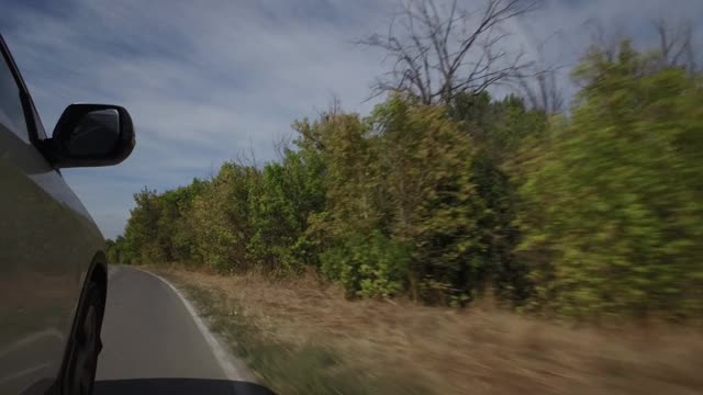 驾驶汽车，POV，特写车轮旋转在乡村道路与树木和蓝天视频素材