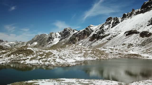 一架无人机拍摄的是奥地利费尔德西科普夫附近的一个湖。湖被雪包围，部分覆盖了阿尔卑斯山脉的石坡。这个湖被陡峭的山峰包围着。冷静视频素材