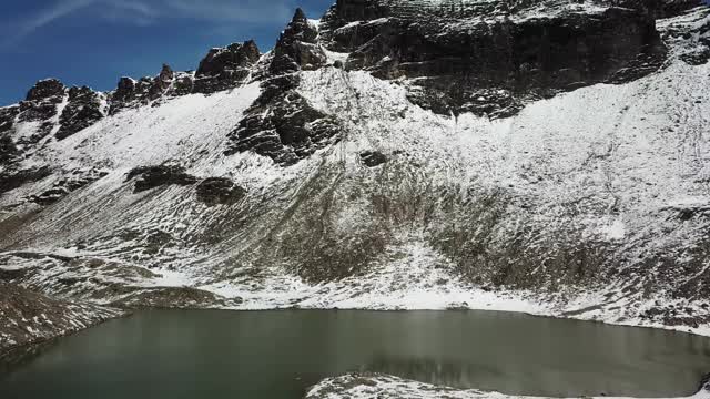 无人机拍摄到奥地利费尔德西科普夫附近的一个心形湖泊。湖被雪包围，部分覆盖了阿尔卑斯山脉的石坡。这个湖被陡峭的山峰包围着视频素材