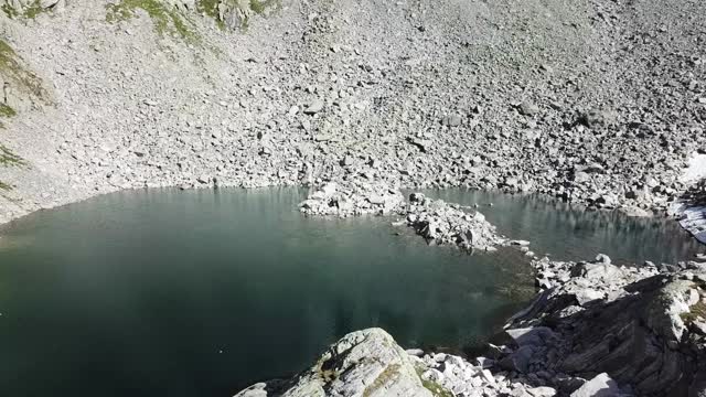 这是一架无人机从上到下拍摄的奥地利Hohe Tauern地区的一个湖泊。湖被许多散落在陡峭的高山山坡上的石头所包围。湖水清澈如水晶。宁静视频素材