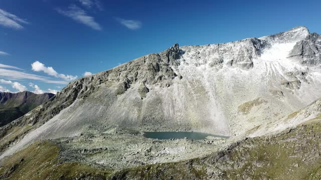 奥地利Hohe Tauern地区斜坡的全景照片。山坡部分被雪覆盖着。上部陡峭而尖锐。阿尔卑斯山的早春。中间有一个小湖视频素材