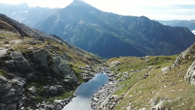 奥地利Hohe Tauern地区斜坡的全景照片。山坡部分被雪覆盖着。上部陡峭而尖锐。阿尔卑斯山的早春。中间有一个小湖视频素材