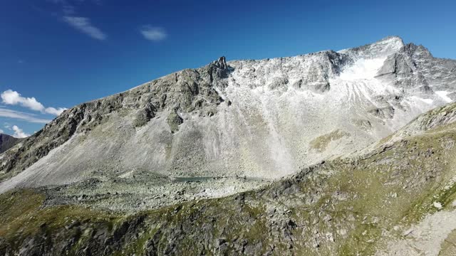 奥地利Hohe Tauern地区斜坡的全景照片。山坡部分被雪覆盖着。上部陡峭而尖锐。阿尔卑斯山的早春。中间有一个小湖视频素材