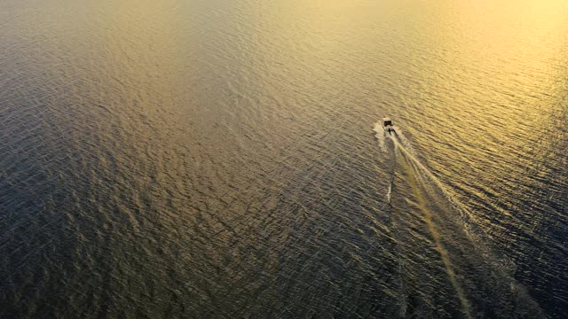 海上移动的渔船鸟瞰图。俯视图帆船渔船。鸟瞰图渔船在日落。水波倒影。海洋中高速行驶的摩托艇。视频素材