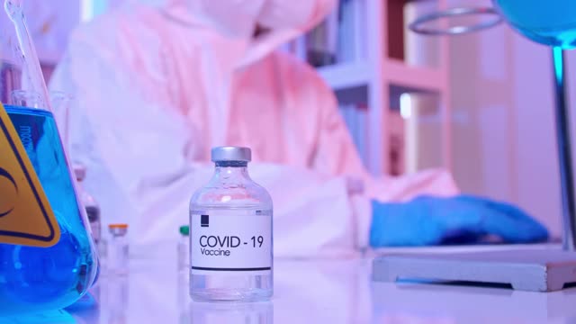 身穿个人防护服的科学家在实验室进行COVID - 19疫苗研究。视频素材