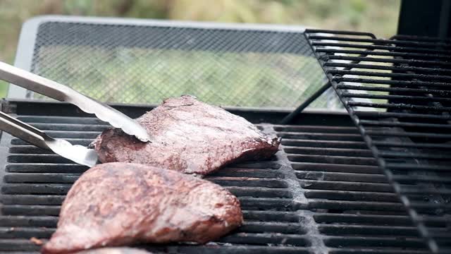 烧烤用热烤架烤的油炸肉。厨师交替用钳子夹肉。视频素材