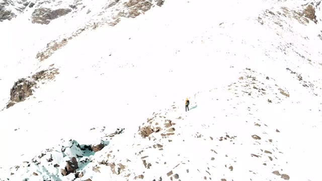 无人机记录下了西班牙比利牛斯山脉雪景中独自徒步的男性。视频素材