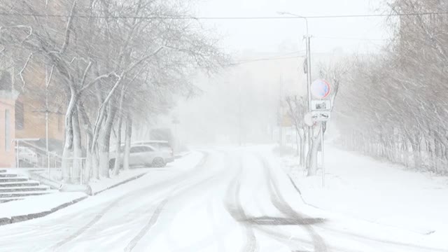 Вlizzard，雾和雪在城市，道路有雨夹雪和轮胎痕迹，能见度差，冬季恶劣的天气视频素材