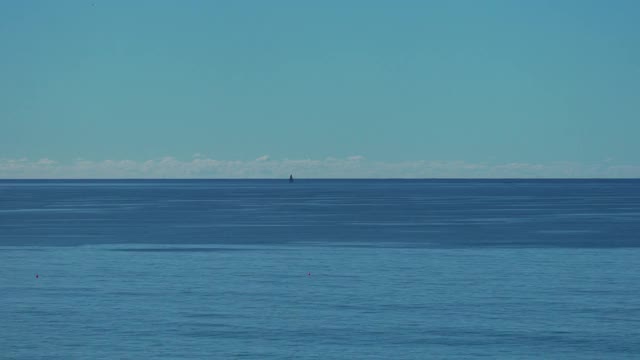 平静的蓝色海洋和地平线上的帆船的时间流逝视频下载