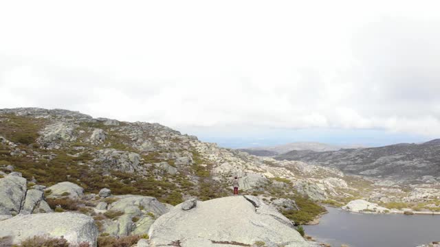 无人机拍摄的女子站在巨石上欣赏Covao dos Conchos的景色，Serra da Estrela视频素材