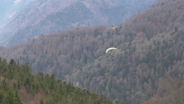 慢动作空中滑翔伞飞越美丽的山覆盖着树木，法国。高质量4k镜头视频下载