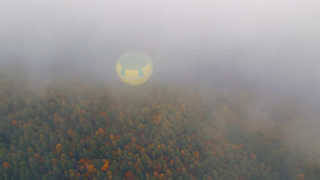 气球飞过秋天的森林，在浓雾和多云的天气，从上面观看。视频素材