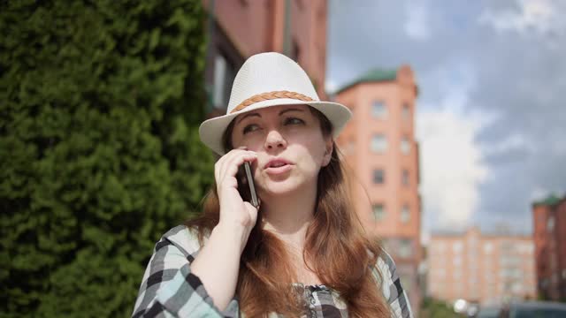 戴着帽子的旅行者女人在城市里打电话，和朋友聊天视频素材