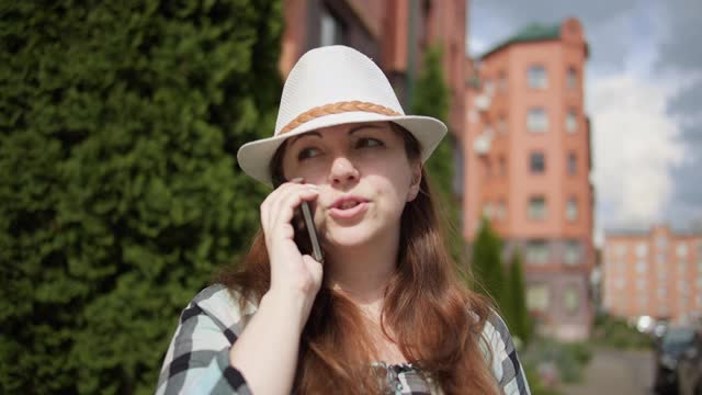 戴着帽子的旅行者女人在城市里打电话，和朋友聊天视频素材