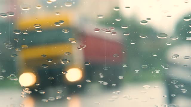 特写雨滴落在汽车挡风玻璃和雨刷清洗他们。视频素材