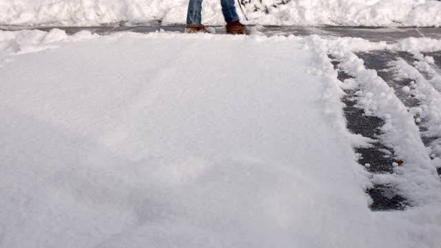 正在从车道或人行道上铲雪的人。视频素材