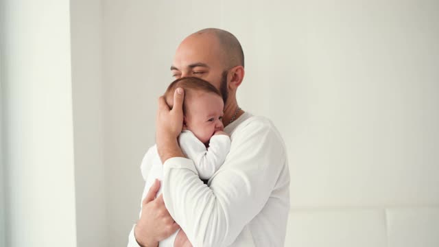 快乐的父亲抱着新生婴儿站在房间里跳舞视频素材