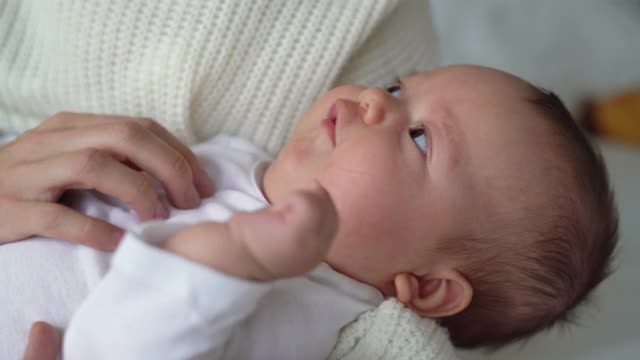 一个新生的婴儿在妈妈的怀里，女人的手正在看。母亲的概念视频素材