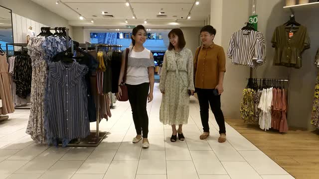 亚洲华人女性在服装店看着镜子挑选衣服视频素材