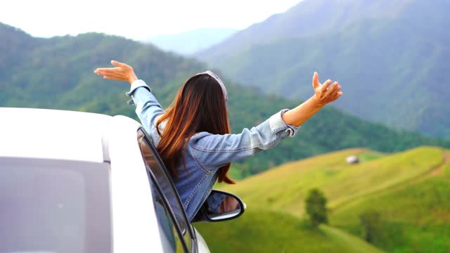 年轻女子旅行者坐在车里看美丽的山景，而旅行驾驶公路旅行的假期视频素材