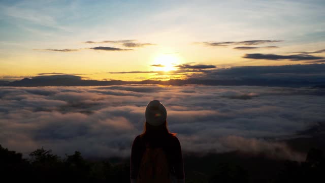 年轻女子旅行者在早晨看日出和山上的雾海，旅行的生活理念视频素材