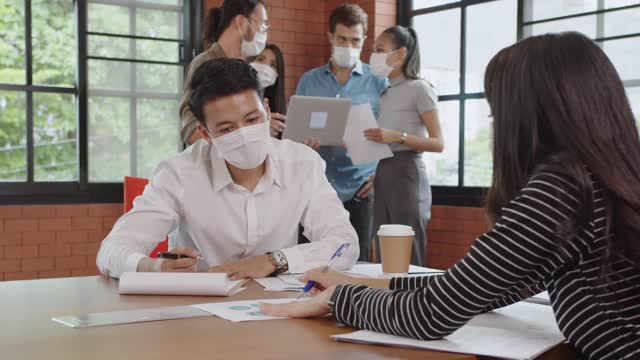 年轻的亚洲商人在冠状病毒大流行期间通力合作。视频素材