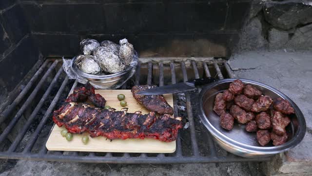 近距离烧烤排骨，猪肉和土豆在木材和木炭烤架上视频素材